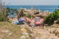 Vendors under colorful umbrellas set up on rocky beach