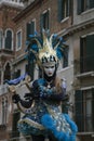 Venice Carnival character dressed in a colourful blue and yellow costume and venetian mask with a harp Venice Italy