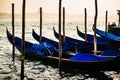 Venetian gondolas at their berth in the markus basin in Venice. Mystic light atmosphere in the early morning with fog in the backg Royalty Free Stock Photo