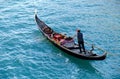 Venetian gondolier carries tourists on gondola in Venice