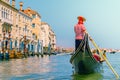 A Venetian gondolier leisurely rows past the historic buildings in the rio grande.