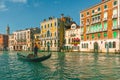 Venetian gondolier punting gondola through Grand Canal along colorful building facades in Venice