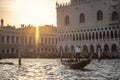 Venetian gondolier punting gondola through green canal waters