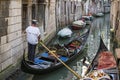 Venetian gondolier in a narrow canal of Venice, Italy