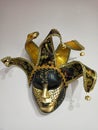 Venetian mask decorated with black and gold sequins, on top of knitted decorative ribbons are miniature bells