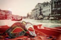 venetian mask on red silk fabric in front of blurry Venice Royalty Free Stock Photo