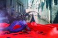 venetian mask on red silk fabric in front of blurry Venice Royalty Free Stock Photo