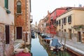 Venetian narrow canal with boats and bright houses.