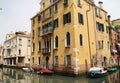 Venetian street, Venice waterway, classical buildings, Venetian architecture, moored boats, shutters, flowers in windows, Italy Royalty Free Stock Photo