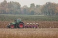 A farmer with his tractor plows the land at the end of the autumn season to prepare it for spring planting