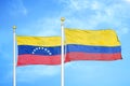 Venezuela and Colombia two flags on flagpoles and blue sky