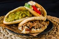 Venezuelan arepas on a black background, made with maize and filled with avocado, tomato, meat, cheese and black beans Royalty Free Stock Photo