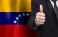 Venezuelan concept. Businessman showing thumb up on the background of flag of Venezuela