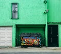 Graffiti Bin in front of a green back alley building