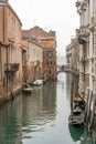 Venice canal scene depicting a small boat in a quiet residential part of Venice in winter on a cool misty day with no people or Royalty Free Stock Photo