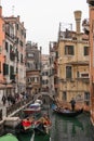 Venice canal scene depicting small boats and gondolas in a residential part of Venice in winter on a cool grey day with a people Royalty Free Stock Photo