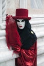 Person at Venice Carnival dressed in a black and red venetian costume and venetian mask with a feather Venice Italy Royalty Free Stock Photo