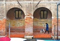 Venice colorful corners with woman walk with dog under arches of old building and windows. Venice, Italy