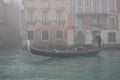 Venice in the fog. Gondolier carries tourists on the canal in the gondola.