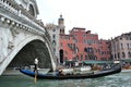 Gondola is passing along the Grand canal under the beautiful Rialto bridge in a sunny spring day.