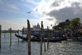 Gondola with tourists in it moving away from the bank in Venice lagoon.