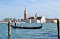 One gondola with tourists and gondolier moving to the San Marco pier in a spring Easter sunny day.