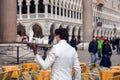 Young waiter in white suits and wearing a face mask working at a terrace cafe in San Marco Square in Venice, Italy