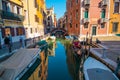 VENICE, ITALY - August 27, 2021: View of empty gondola on narrow canals, with a tourist waiting for the gondolier of Venice, Italy