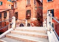 Venice, Italy. Small bridge with concrete steps and traditional orange historic buildings. Royalty Free Stock Photo