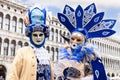 A couple of participants in the Venetian carnival in the original masks on Piazza San Marco Royalty Free Stock Photo