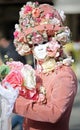 Venice, Italy - February 5, 2018: person with pink dress and white mask during the Venetian Carnival