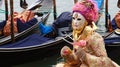 VENICE, ITALY - FEBRUARY 23, 2017: An unidentified masked person in costume during the Carnival of Venice with gondolas on the bac Royalty Free Stock Photo