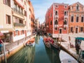 Venice, Italy - 17.10.2023: Gondolas waiting for passengers, Stunning colorful buildings in the background. Warm sunny day. Travel