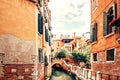 Venice, Italy. Couple walking near small bridge over canal surrounded by traditional orange historic buildings.