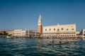 Venice,Italy-January 29,2022.Famous San Marco square with Doges Palace,bell tower on sunny day,people paddling on boat.Early Royalty Free Stock Photo