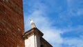 VENICE, ITALY - JULY 7, 2018: close-up view of lonely seagull sits on top of a building against a blue sky. on Royalty Free Stock Photo