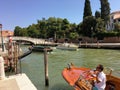 water taxi driver waiting for business inside his traditional wooden taxi boat along the side of a canal during a busy summer day Royalty Free Stock Photo