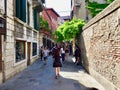 A young female tourist and other tourists walking down an old beautiful Venetian street