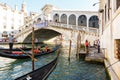 View of gondola and Ponte di Rialto, many tourists on a bridge. Sunset in Venice Royalty Free Stock Photo