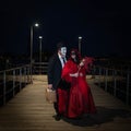 A Man and a Woman in Venetian Carnival costumes standing on wooden pier at Grand Canal, Venice at Night