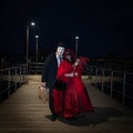 A Man and a Woman in Venetian Carnival costumes standing on wooden pier at Grand Canal, Venice at Night Royalty Free Stock Photo