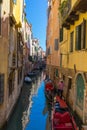 VENICE, ITALY - May 23, 2016: Gondolier taking care of two anchored gondolas in Venice canal with clear sky Royalty Free Stock Photo