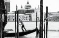 A gondolier or venetian boatman propelling a gondola on Grand Canal in Venice. Black and white Royalty Free Stock Photo