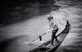 A gondolier or venetian boatman propelling a gondola on Grand Canal in Venice. Black and white