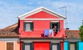 Local woman putting the laundry to dry at the window. Local traditional scene from Burano, Italy