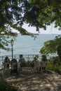 People seating outdoors overlooking Venice lagoon from its Giardini