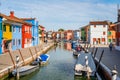 Picturesque colorful idyllic scene with a boats docked on the water canals in Burano Venice Italy.