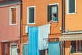 Senior local woman putting the laundry to dry at the window. Local traditional scene from Burano,