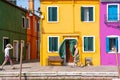 Tranquil scene with tourists and locals strolling along the colorful houses in Burano island, Venice