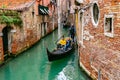 Smiling attractive Caucasian man and woman tourist couple riding in gondola. Gondolier standing on back. Venice, Italy Royalty Free Stock Photo